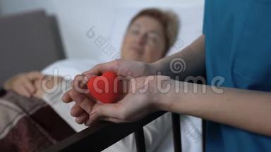 护士手里拿着玩具心在病床上生病的女人的背景，善良